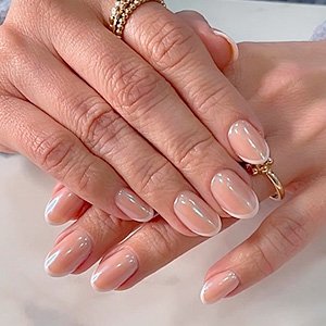 imagen de manos femeninas con esmalte de uñas con decoración estilo francesa