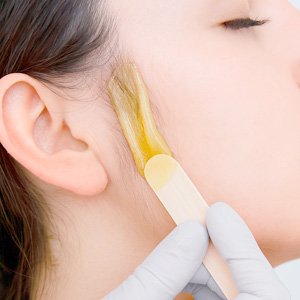 Mujer a la que se le hace una depilación de patillas con cera